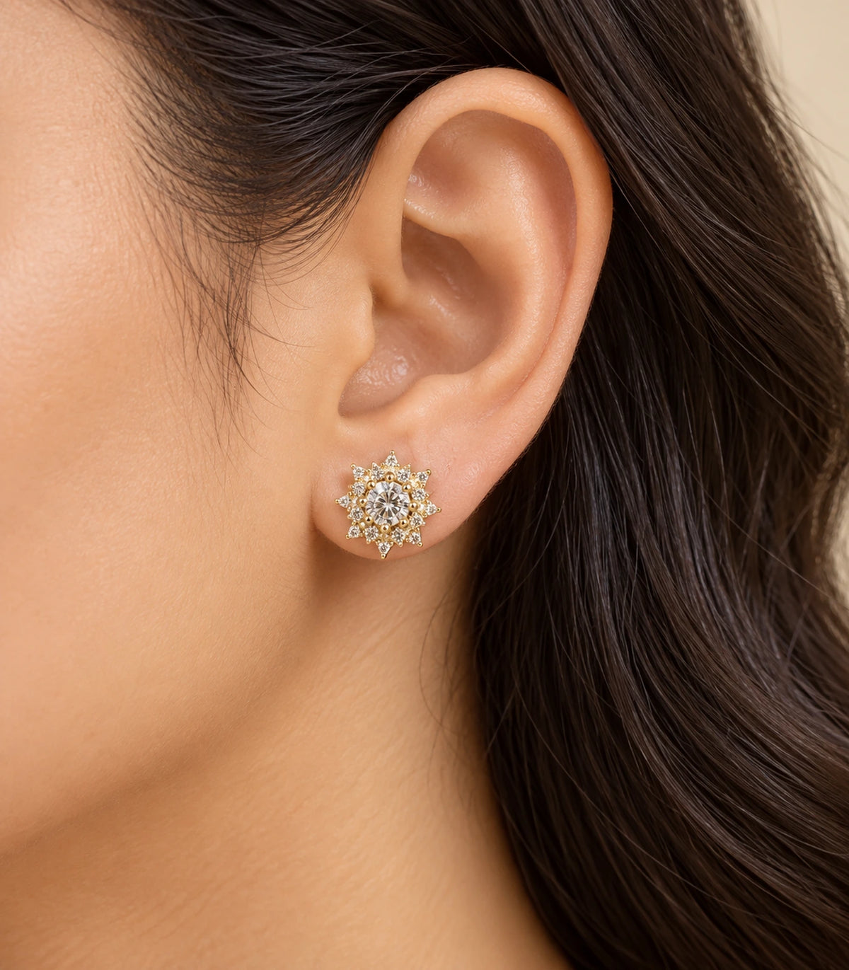 Styled worn view of a gold-tone crystal sunburst stud earring