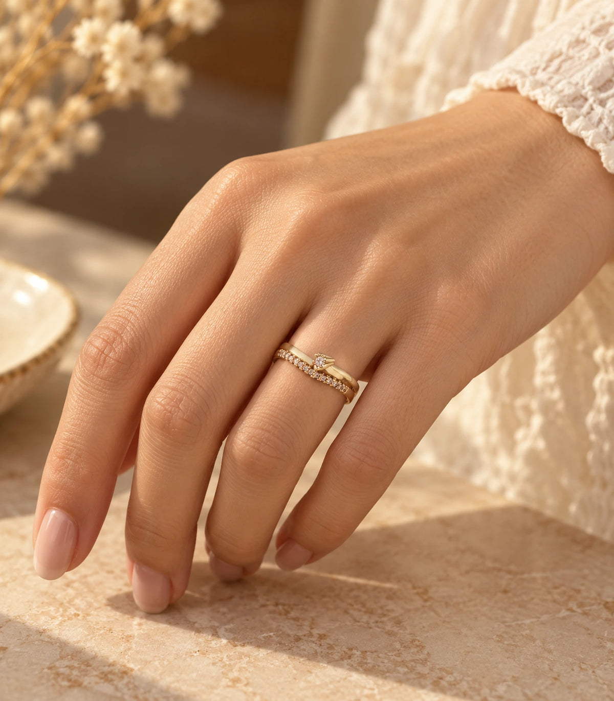 Gold crystal wishbone arrow ring worn on a hand in warm light with a textured cuff