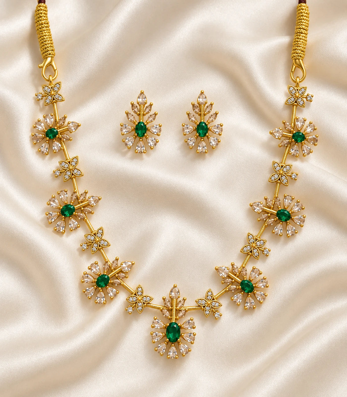 Gold Emerald Floral Crystal Necklace Set with matching earrings arranged on cream fabric