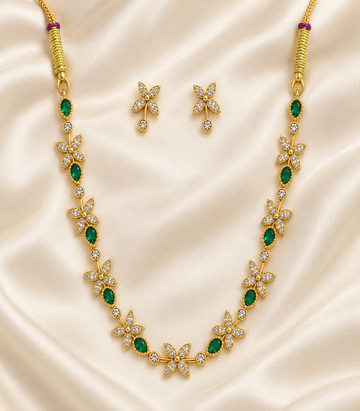 Gold Emerald Floral Crystal Necklace Set with matching earrings arranged on fabric