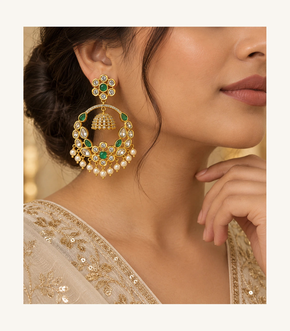 One gold-tone green floral chandbali earring worn with an embellished ivory garment in a distinct three-quarter editorial pose