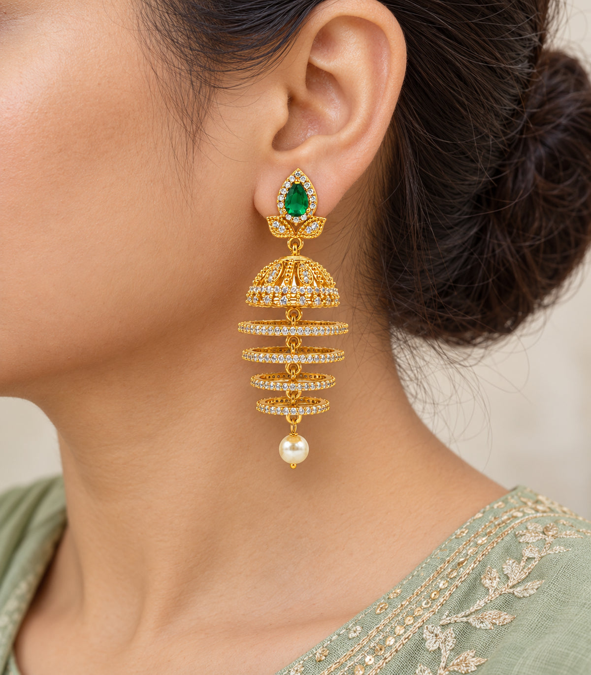 Close-up worn view of the complete earring with green teardrop top, clear-stone bell, four hoops and pearl-style drop