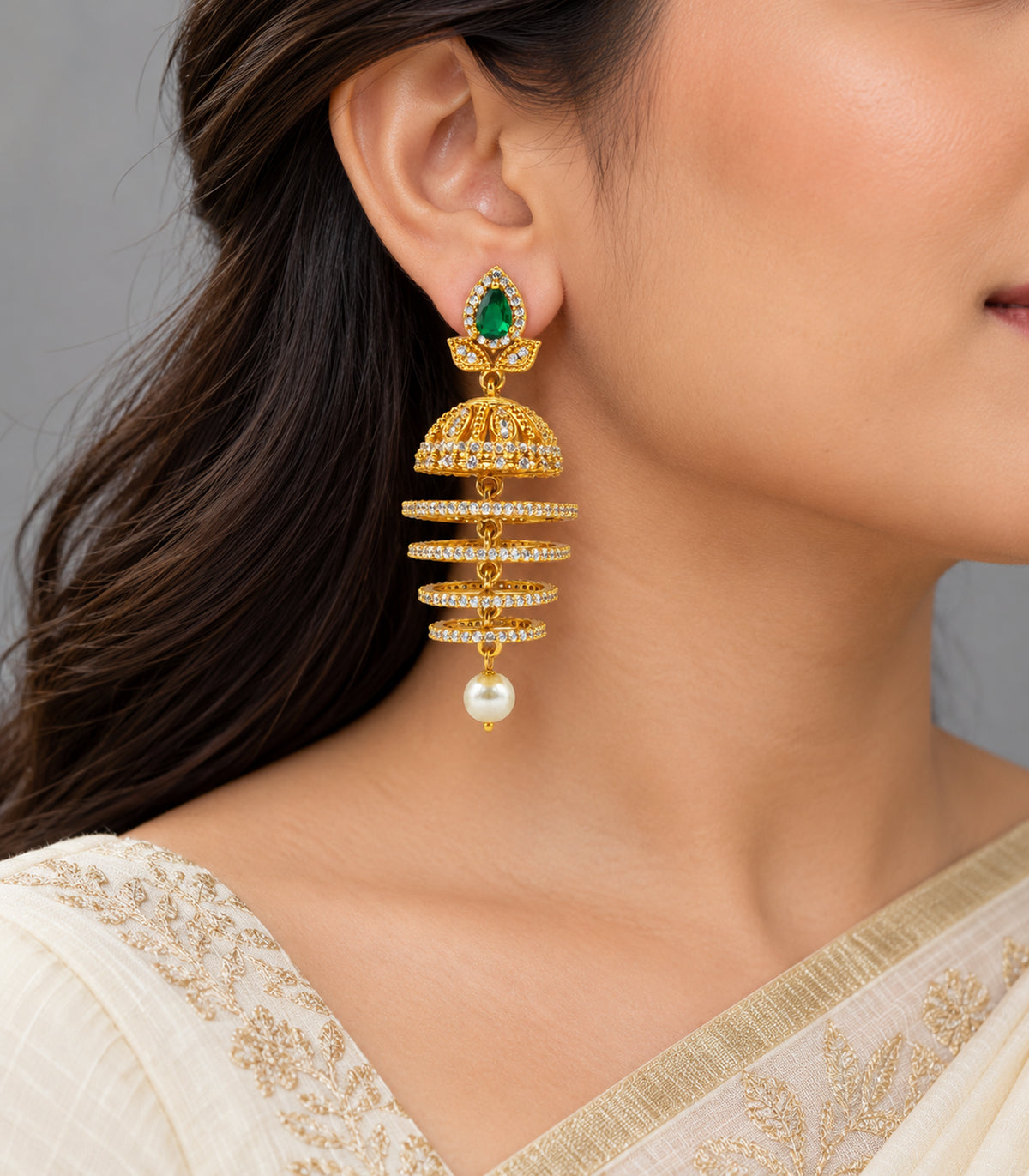 Single earring worn naturally with ivory clothing, showing the green teardrop top, bell, four hoops and pearl-style drop