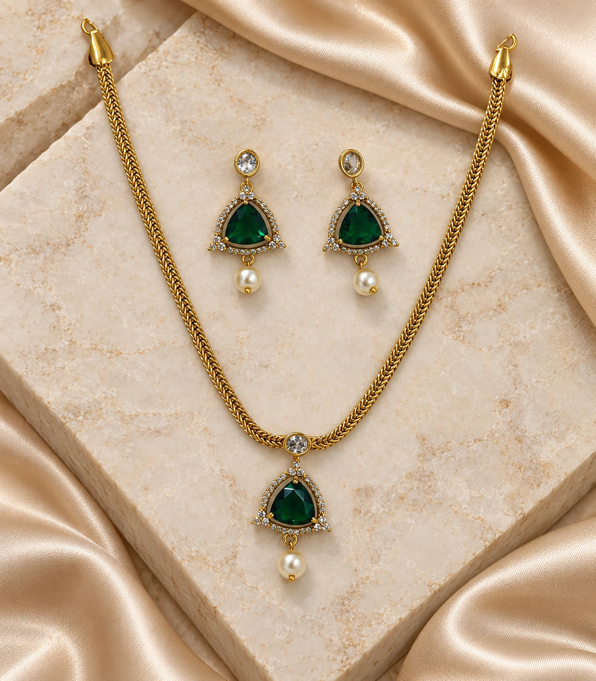 Complete gold emerald-green necklace and matching earring pair on stone and satin