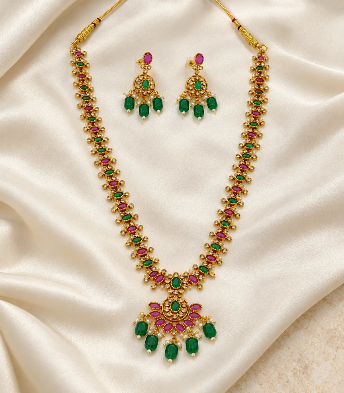 Gold Green Magenta Fringe Necklace Set with matching earrings arranged on cream fabric