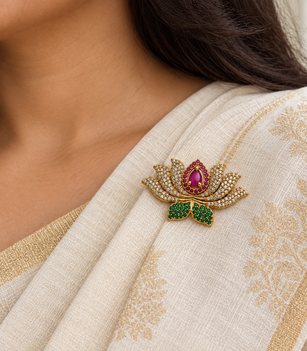 Close view of the magenta lotus brooch with clear petals and green leaves on cream fabric