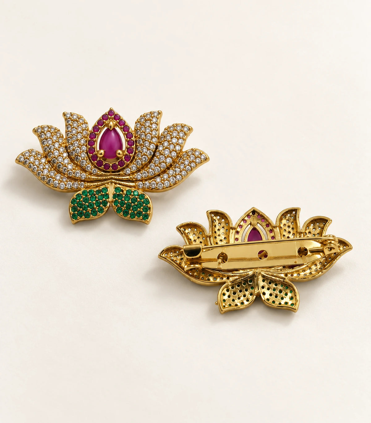 Front and reverse views of the gold-tone magenta lotus brooch on a cream surface