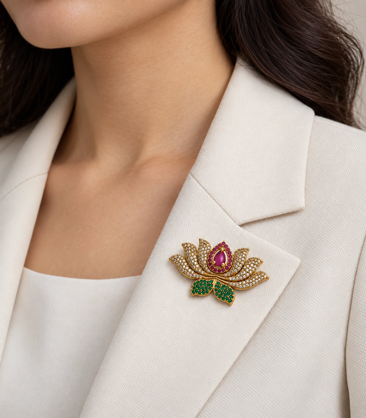 Gold-tone magenta lotus brooch styled on a cream jacket lapel
