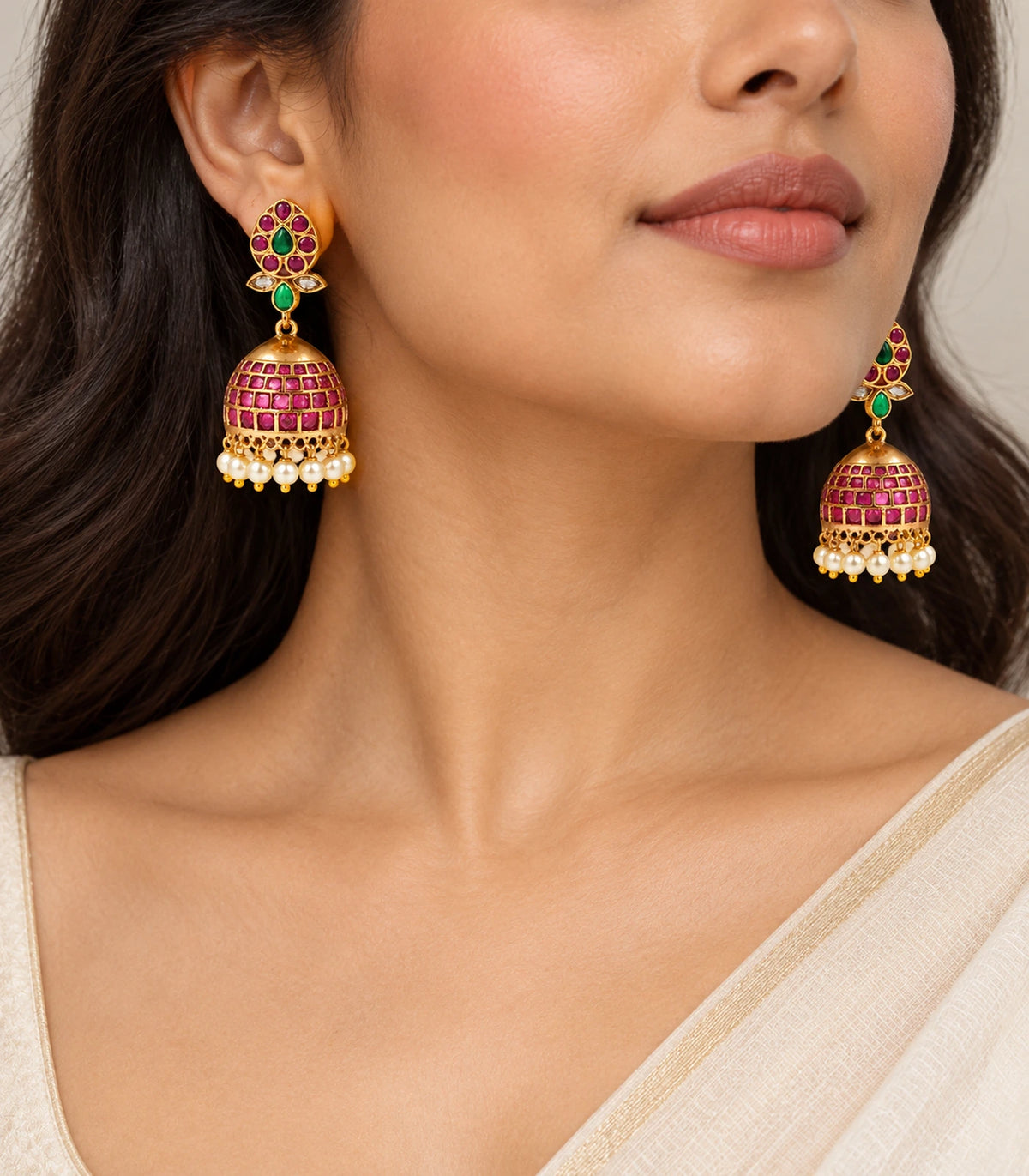 Gold-tone magenta and green pearl-fringe jhumka earrings worn with ivory and gold clothing
