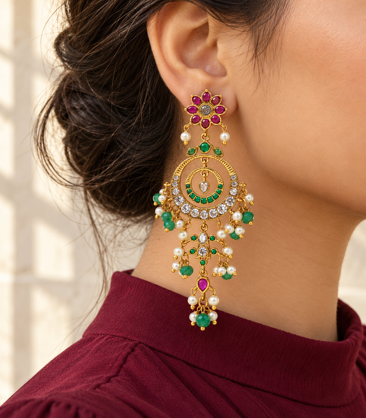 Single chandelier earring worn with burgundy high-neck styling in a back three-quarter view