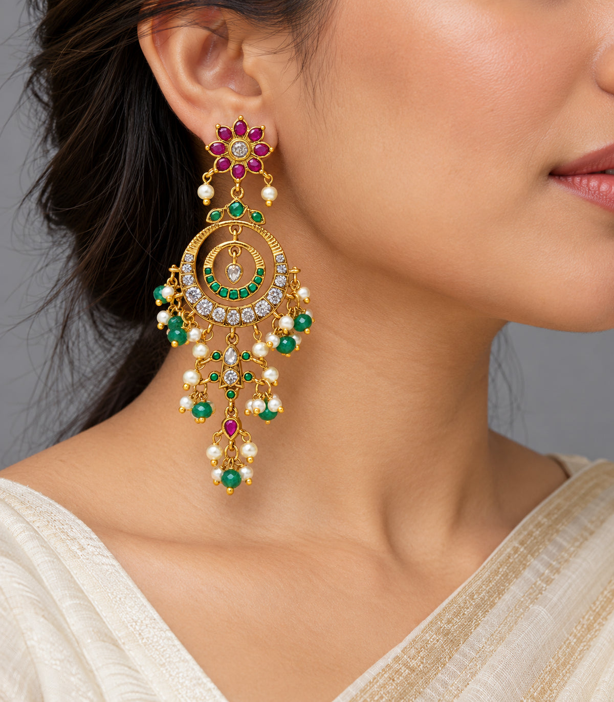 Gold-tone magenta and green chandelier earring worn in a single-ear view with ivory sari styling