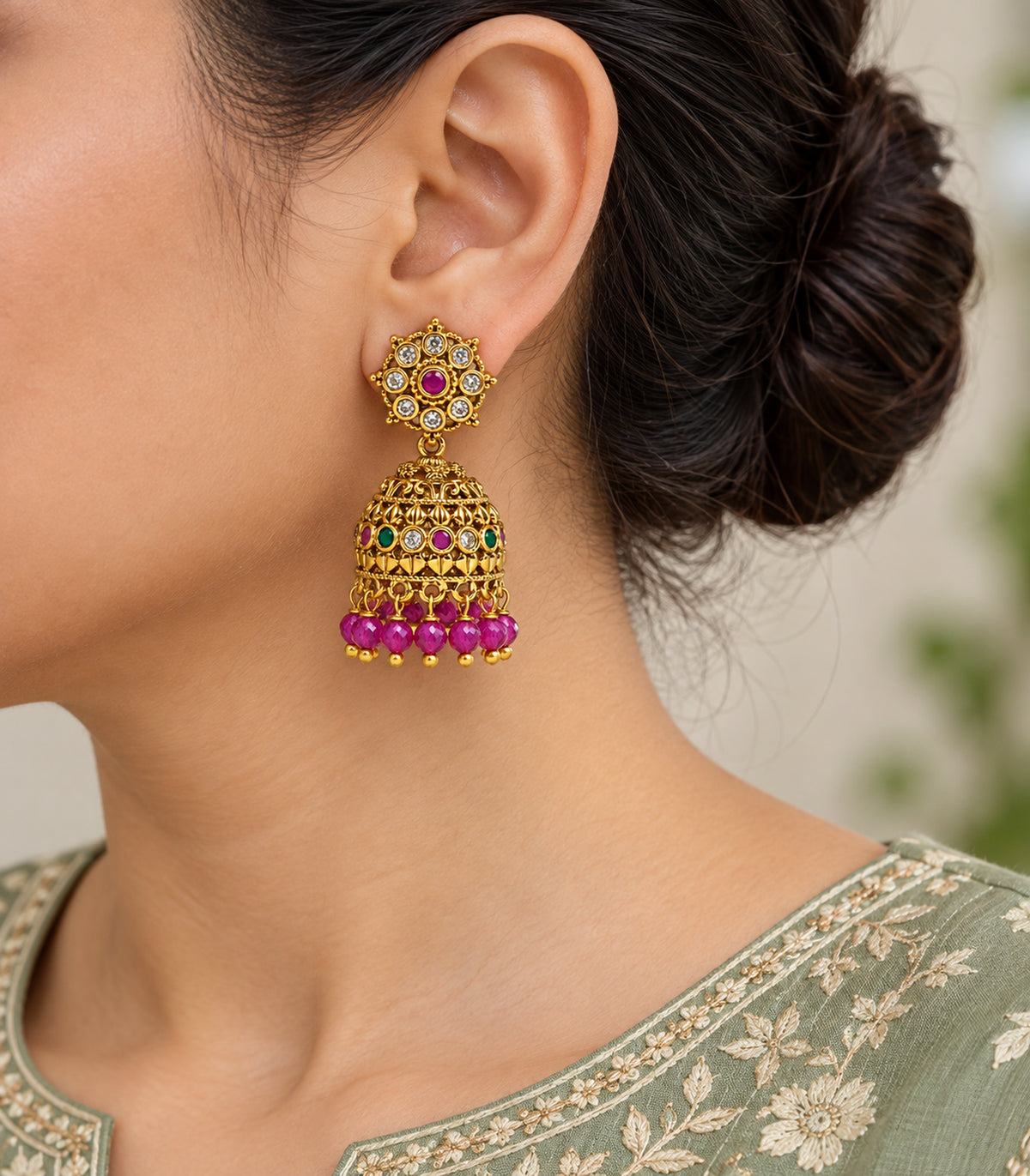 Close view of a worn floral-top jhumka with magenta bead fringe