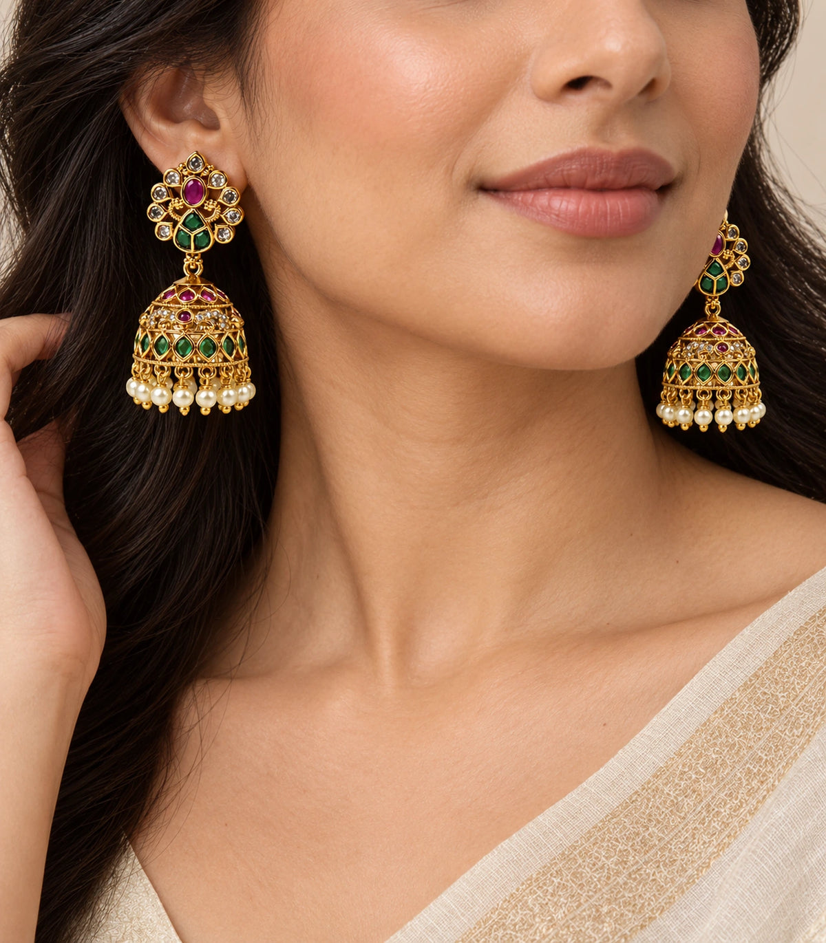 Gold-tone magenta and green peacock jhumka earrings worn with an ivory outfit