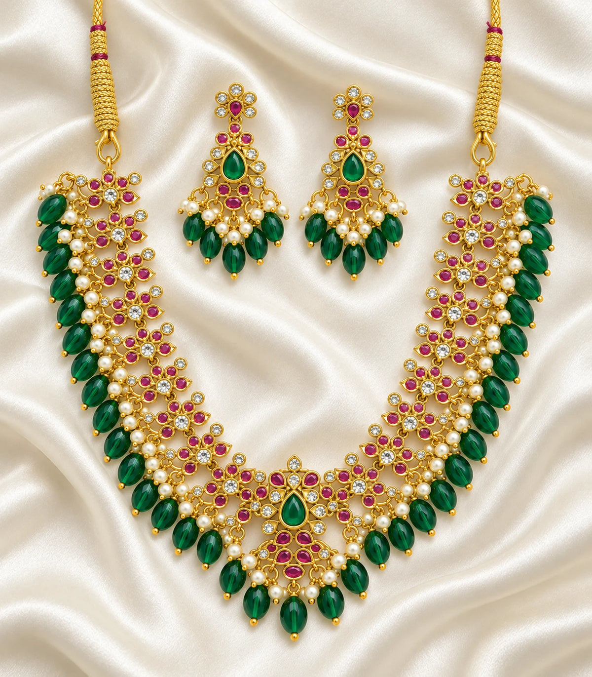 Magenta and green floral necklace with matching earring pair on ivory fabric