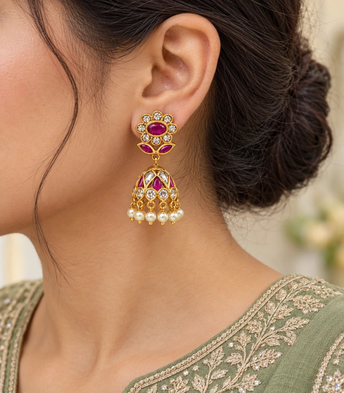 Worn closeup of gold magenta floral jhumka earrings, clear stones, magenta leaves and pearl drops