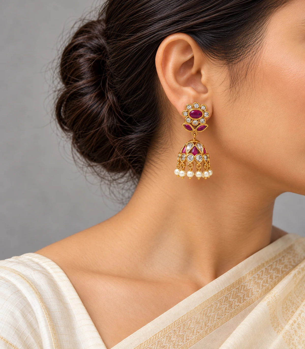 Gold magenta floral jhumka earrings worn with a cream outfit, floral studs and pearl fringe