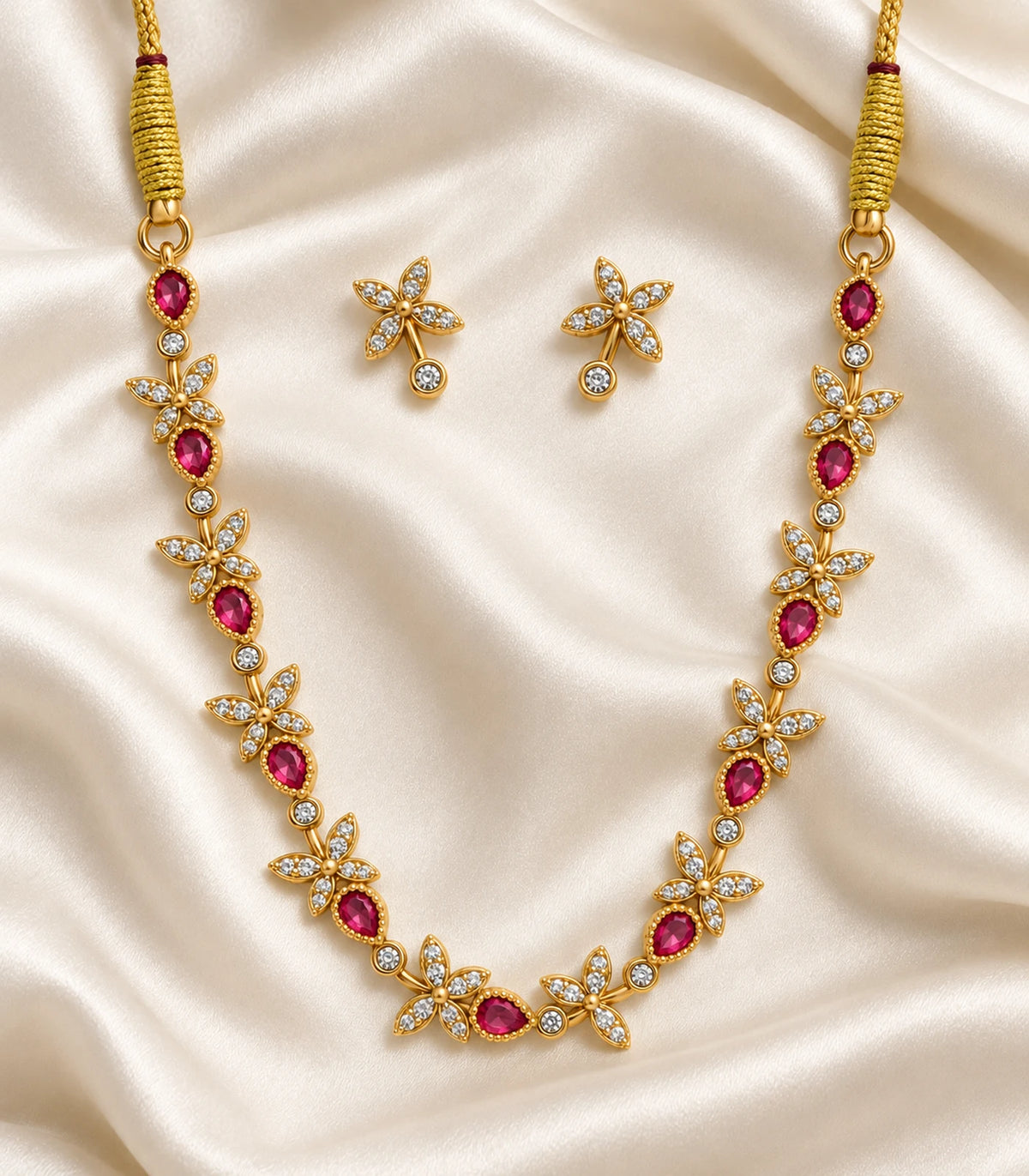 Gold Magenta Leaf Crystal Necklace Set and matching clear earring pair arranged on ivory fabric