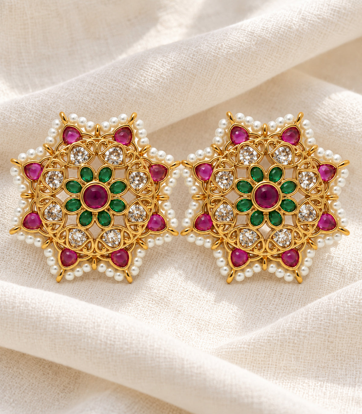 Matching gold magenta and green pearl border studs in a styled flat lay