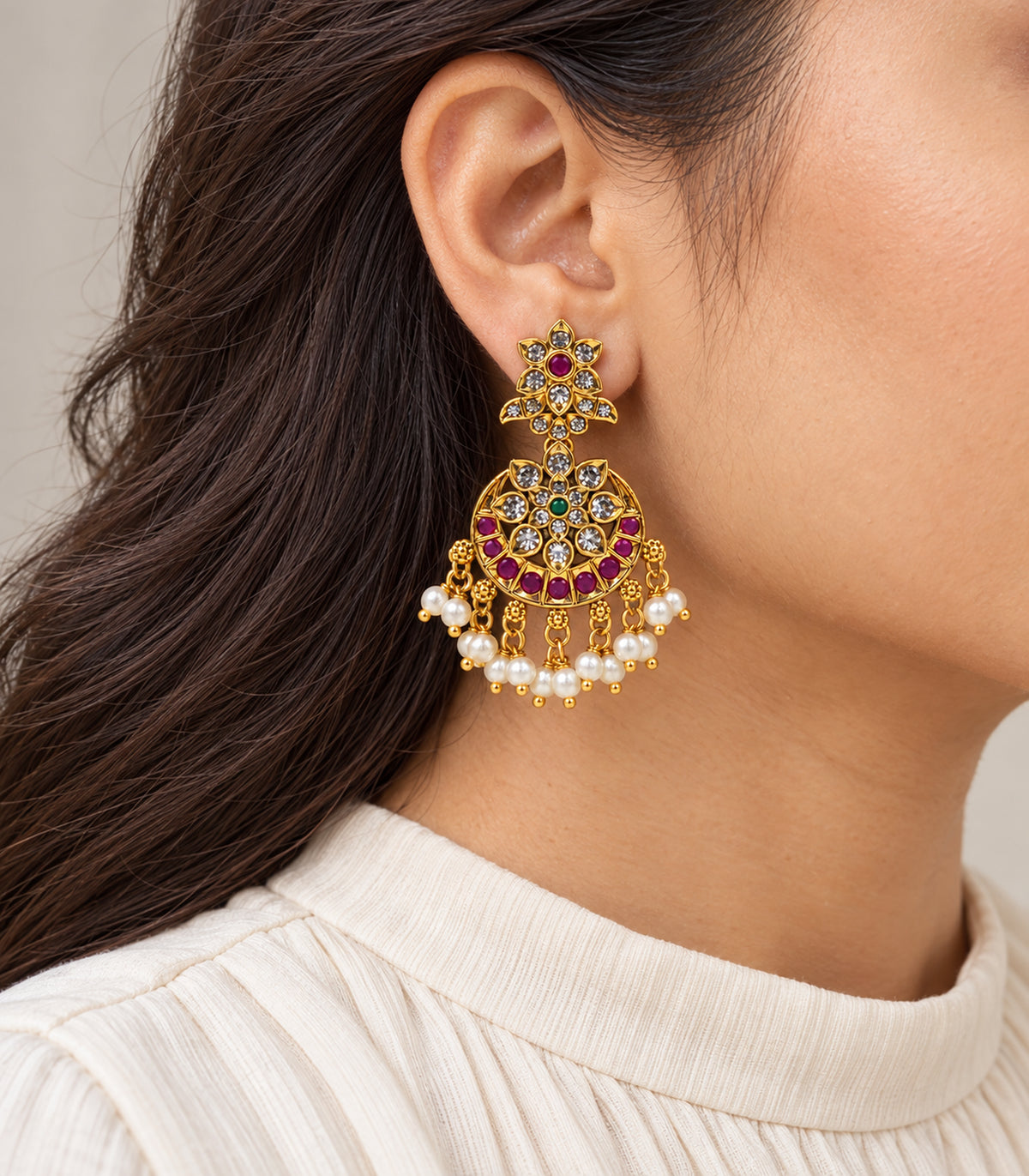 Gold, magenta and green floral pearl chandbali earring shown worn in a side view