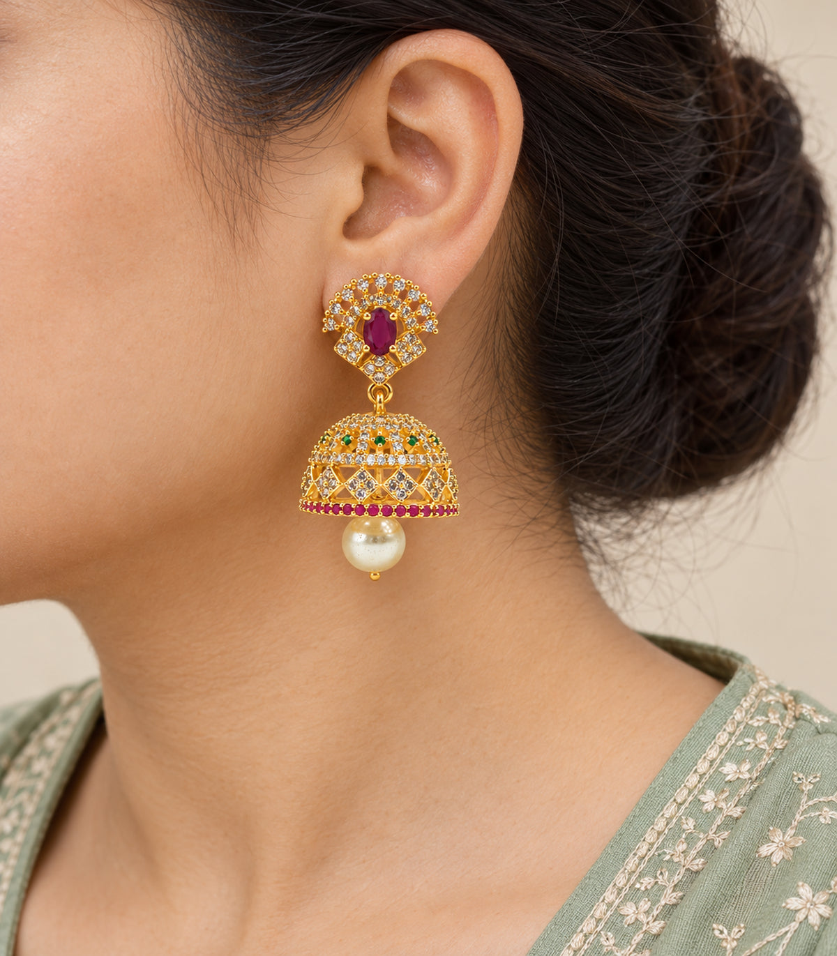 Close-up of the magenta oval, clear fan, green-accented bell and pearl-like drop worn at the ear