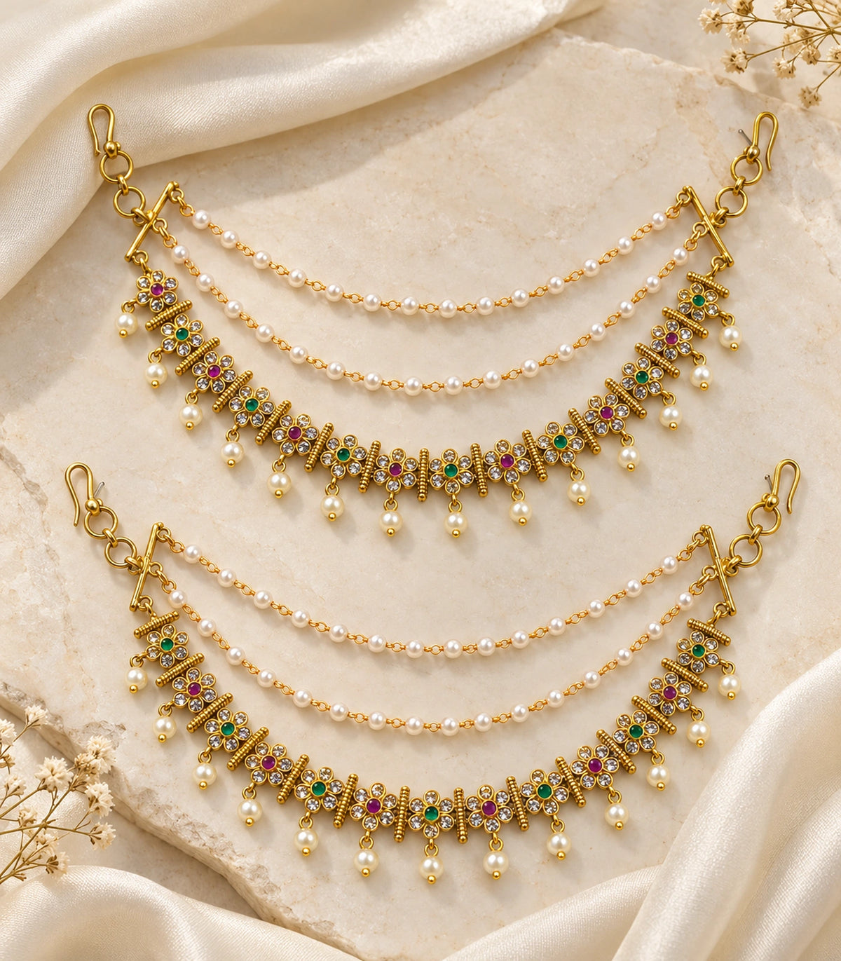 Gold tone magenta and green floral pearl ear chain pair arranged on ivory silk and stone