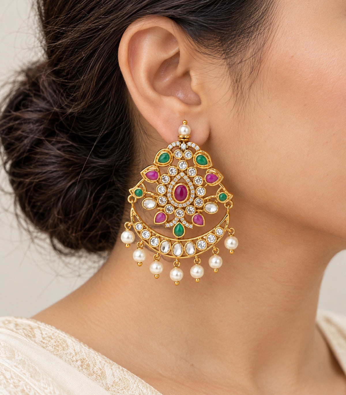 Closeup of the gold magenta and green chandbali earring and pearl-style fringe