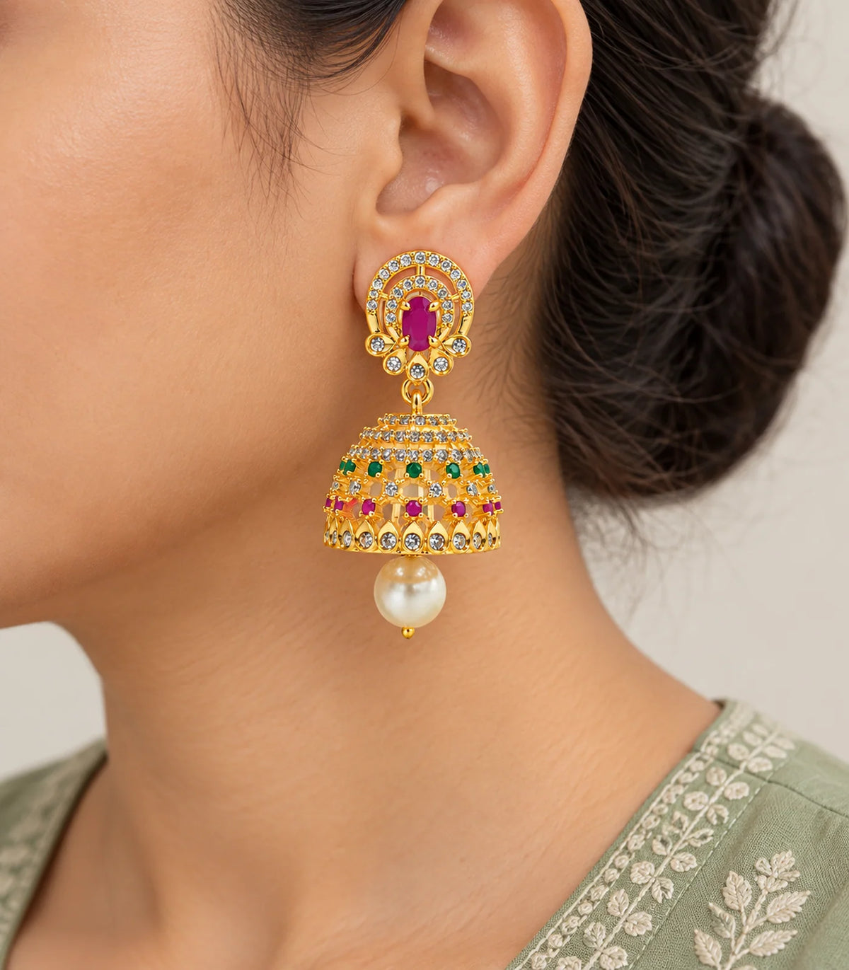 Close worn view of the magenta oval stud, multicolor openwork dome and cream pearl-like drop