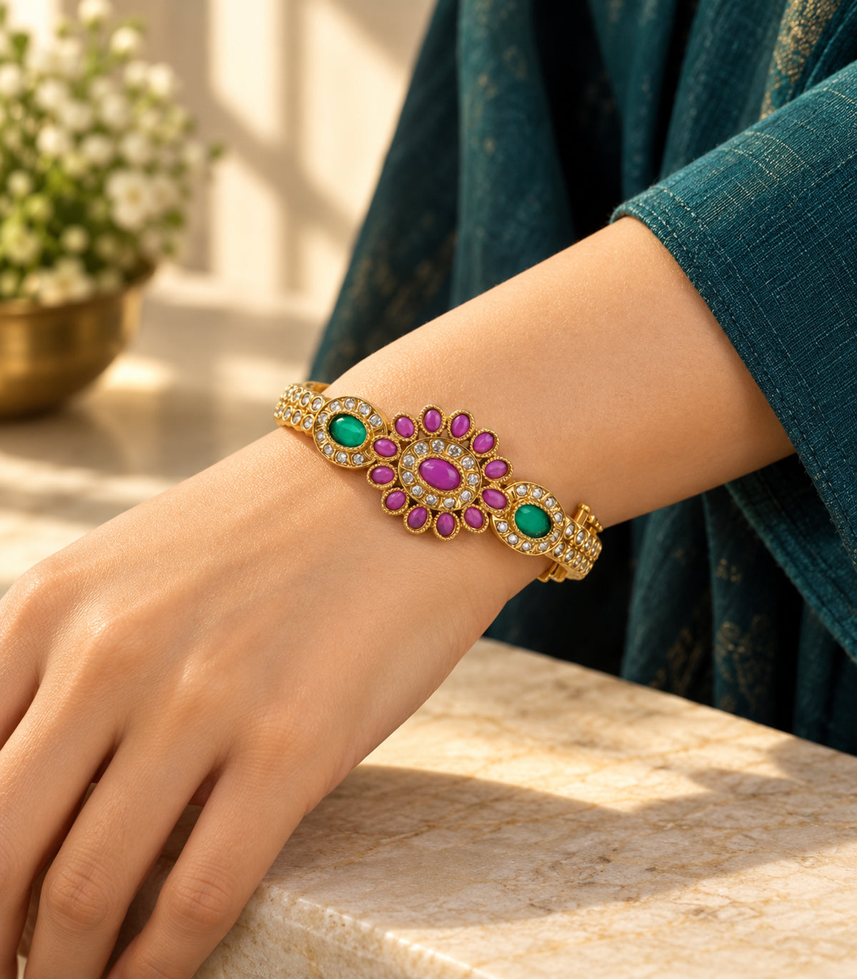 Gold magenta oval flower green halo bangle worn with a dark teal sleeve