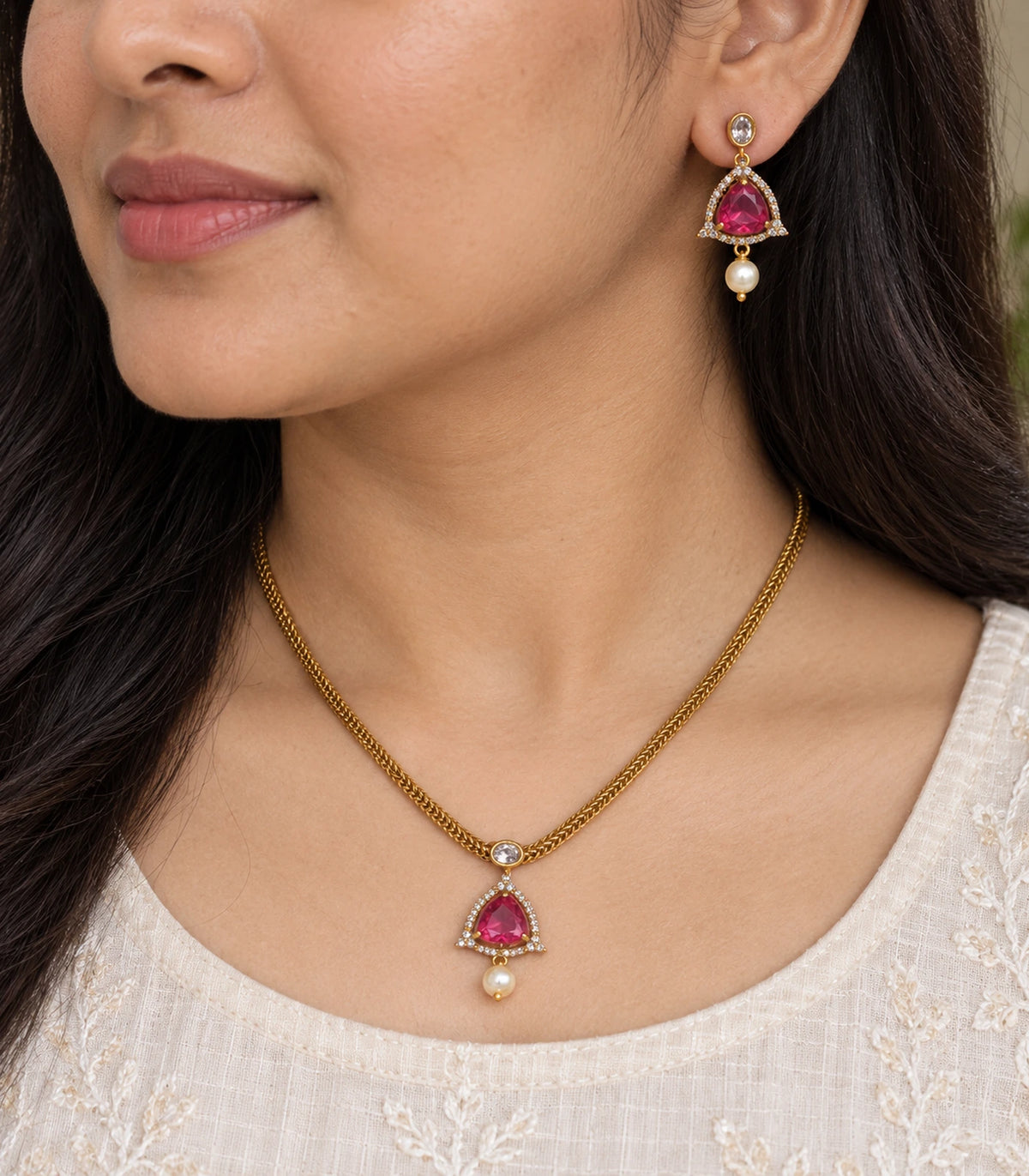 Close view of the magenta pendant and matching pearl-drop earring worn naturally