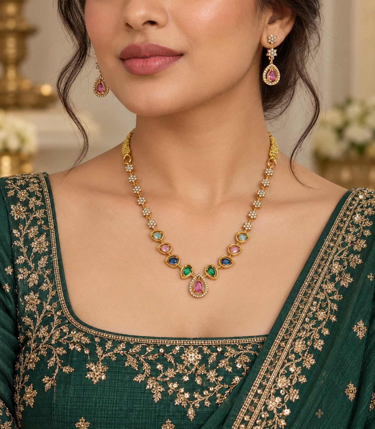 Gold-tone multicolour necklace and matching pink-drop earrings worn with a dark green outfit