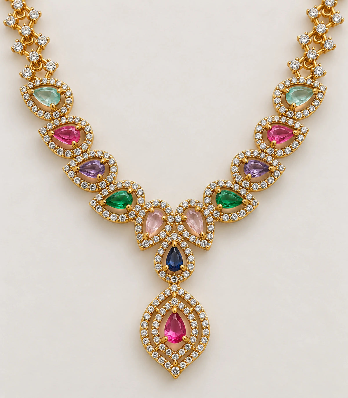 Detail of the multicolor teardrop settings, blue centre accent and pink pendant of the gold-tone necklace
