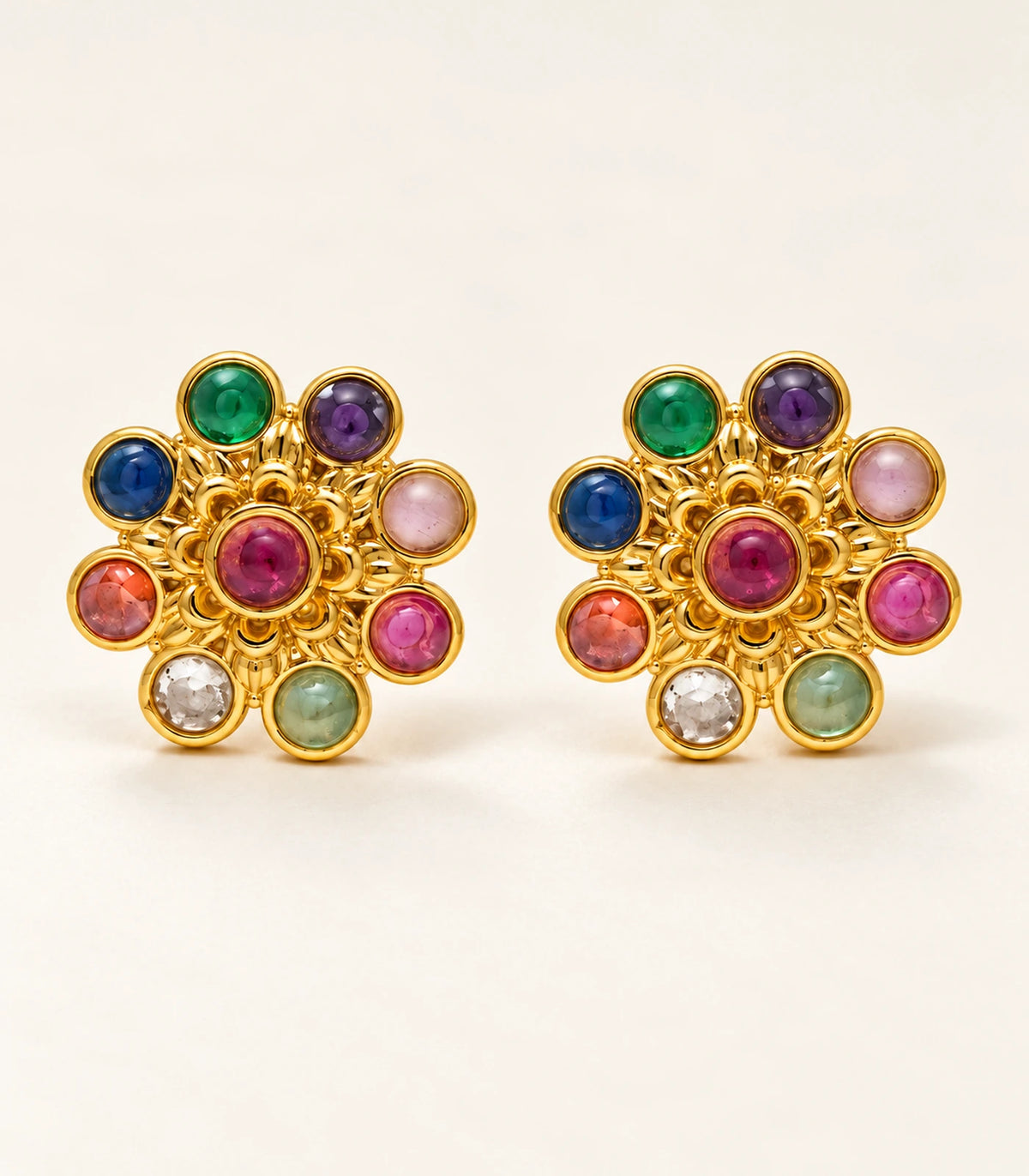 Complete pair of gold-tone multicolour flower stud earrings on a neutral fabric surface