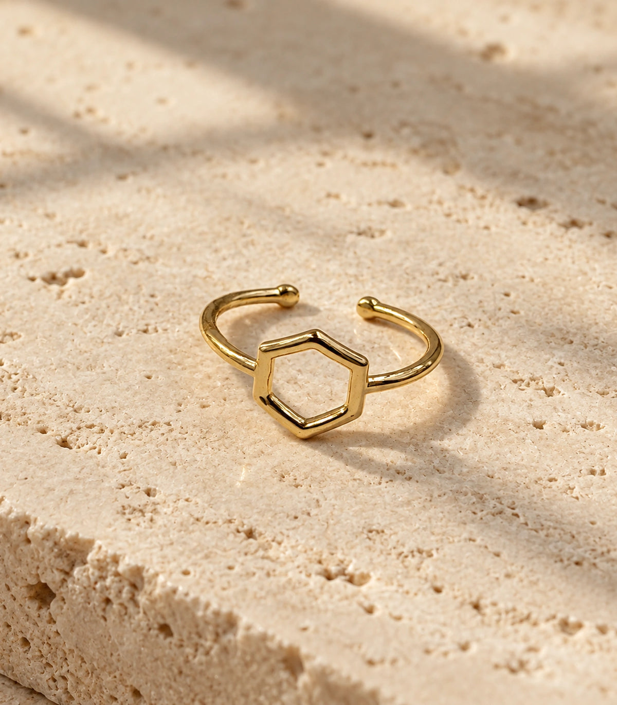 Gold Open Hexagon Minimal Ring with its open band and rounded tips on a stone surface