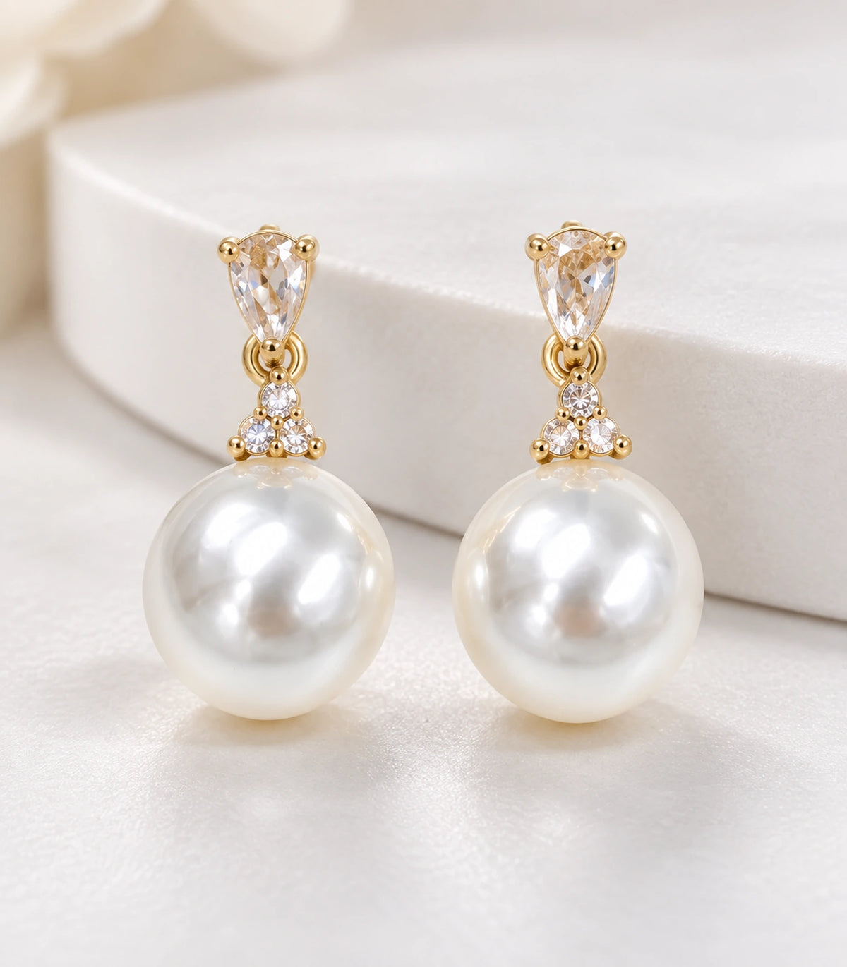 Detailed view of the matching pair, showing pear-shaped tops, three round crystal-style accents and white pearl-style drops.