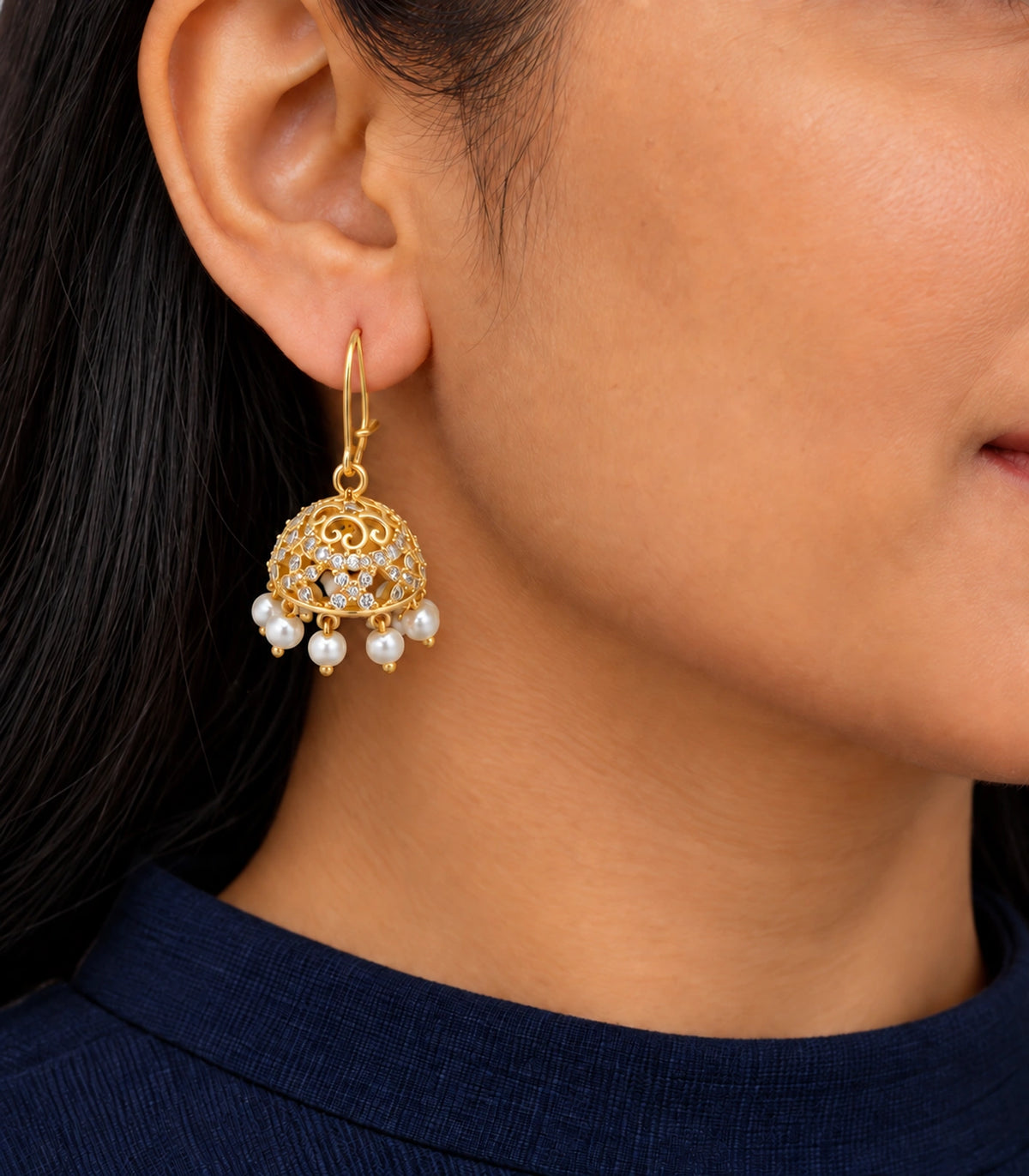 Gold Scrollwork Crystal Jhumka Earrings in Gold — earring worn with navy clothing and closed kidney-wire clasp #color_gold