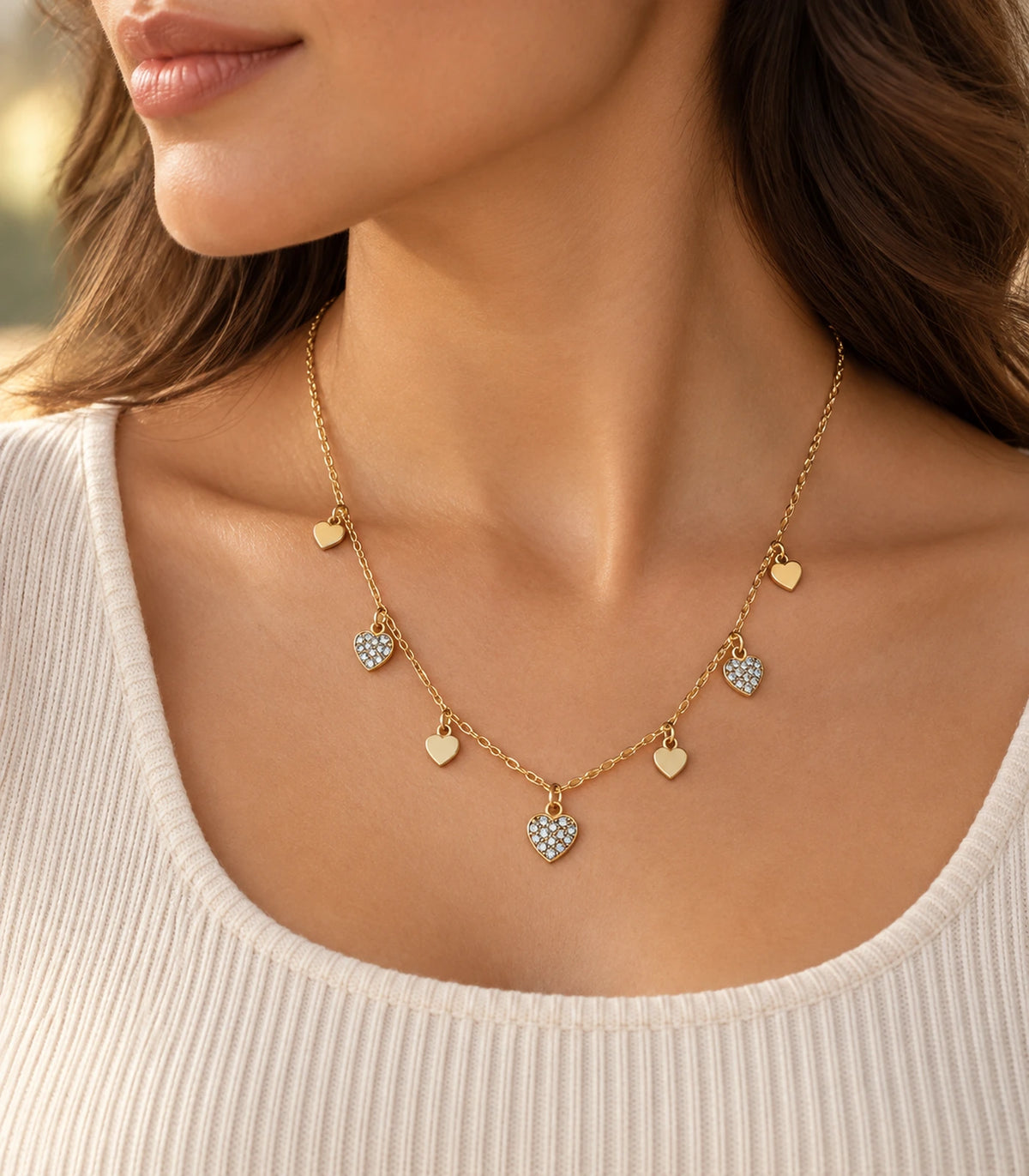 JIMIKI adjustable gold-tone seven heart charm necklace, alternate angled worn view of the gold-tone heart charms #color_gold