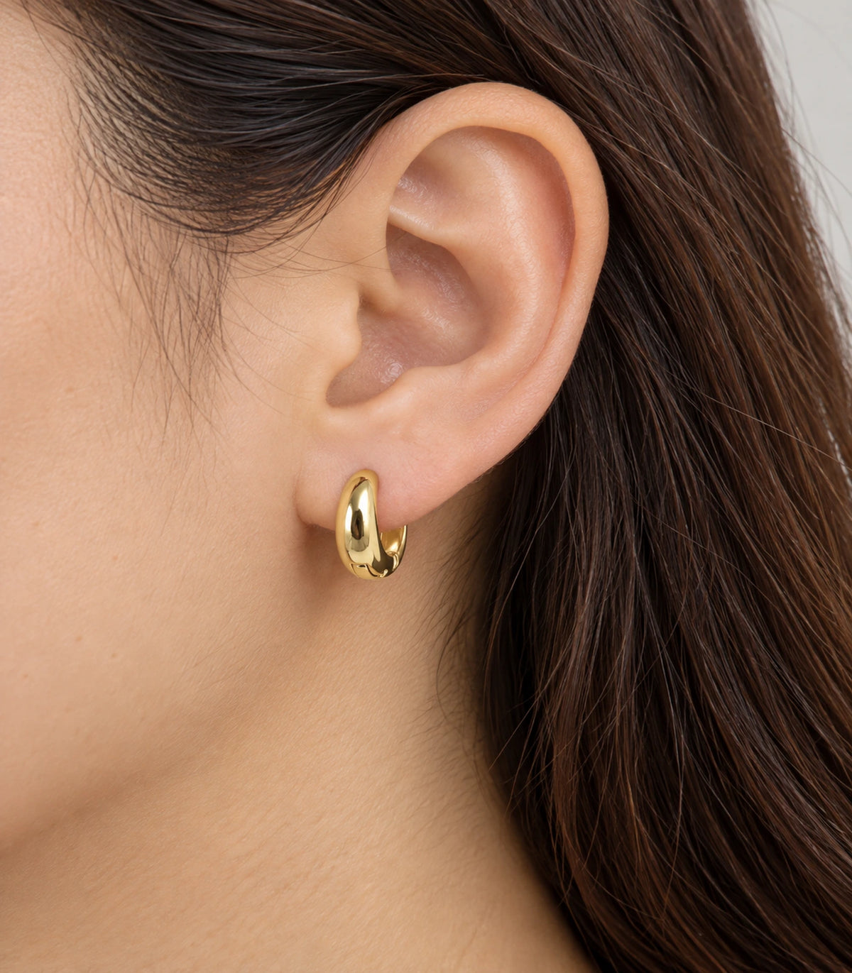 JIMIKI Smooth Tapered Huggie Earrings in Gold Tone — worn styling view #color_gold-tone