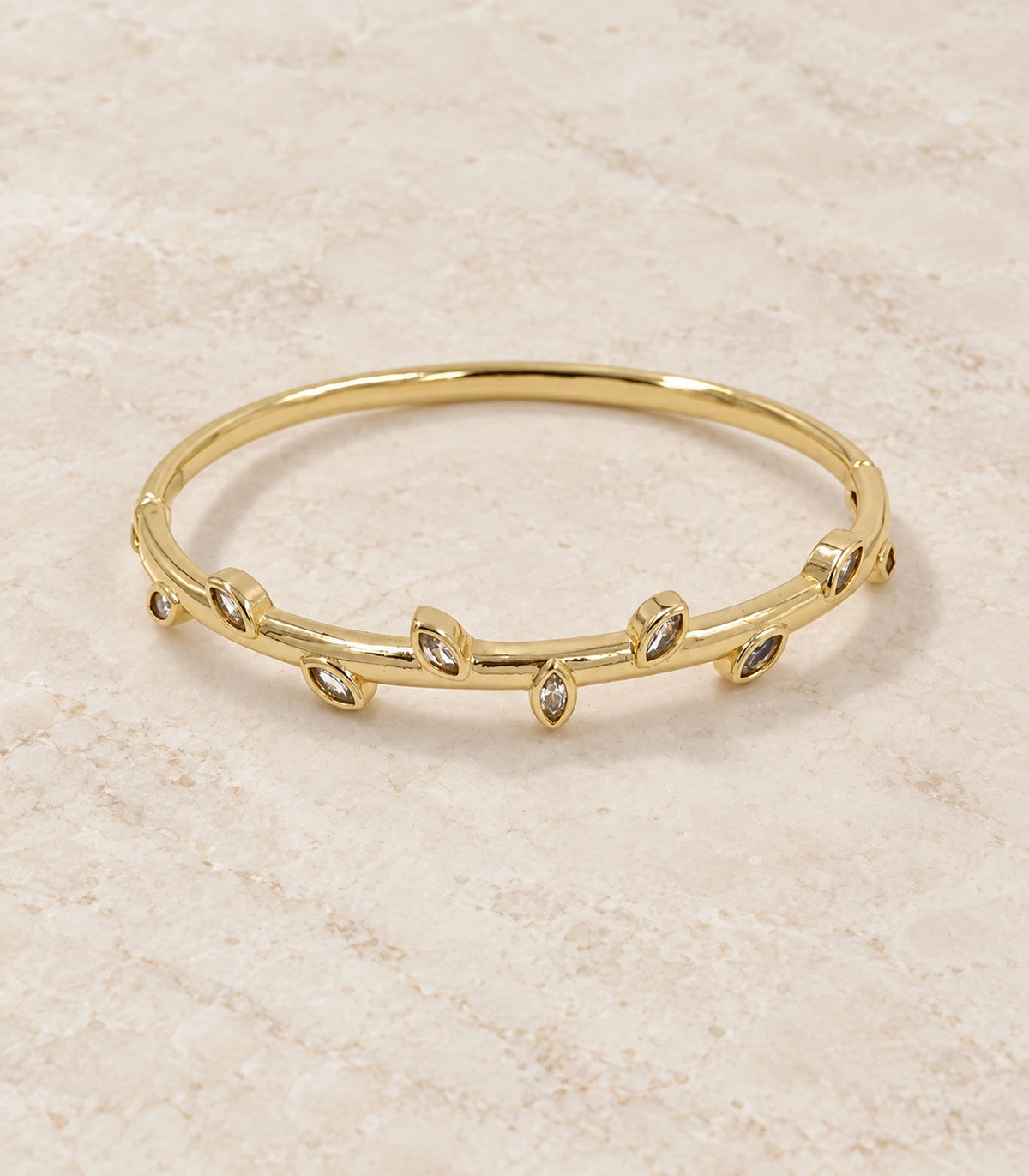 JIMIKI Gold-Tone Alternating Marquise Crystal Bangle — bangle in a styled flat lay #color_gold-tone / clear