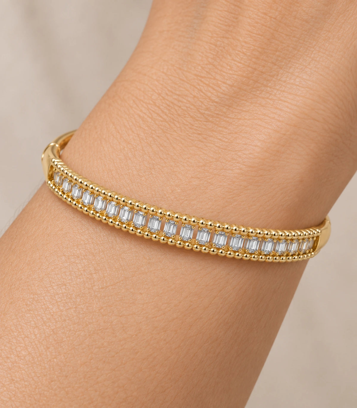 JIMIKI Gold-Tone Baguette Beaded Frame Bangle — close-up of the bangle worn on the wrist #color_gold-tone / clear