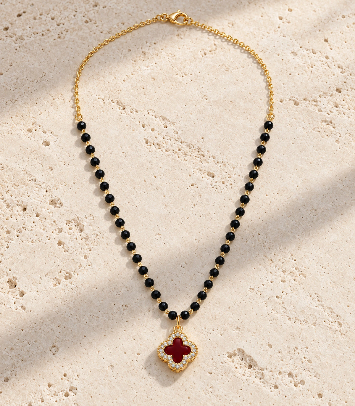 JIMIKI Gold-Tone Black-Bead Red-Quatrefoil Pendant Necklace in Gold Tone / Black / Red - editorial flatlay #color_gold-tone-black-red