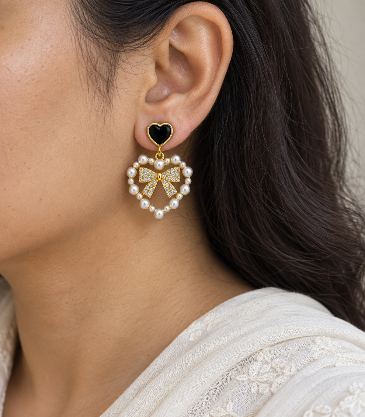 JIMIKI Heart Pearl Bow Drop Earring Pair in Gold Tone / Black, model wearing view #color_gold tone / black