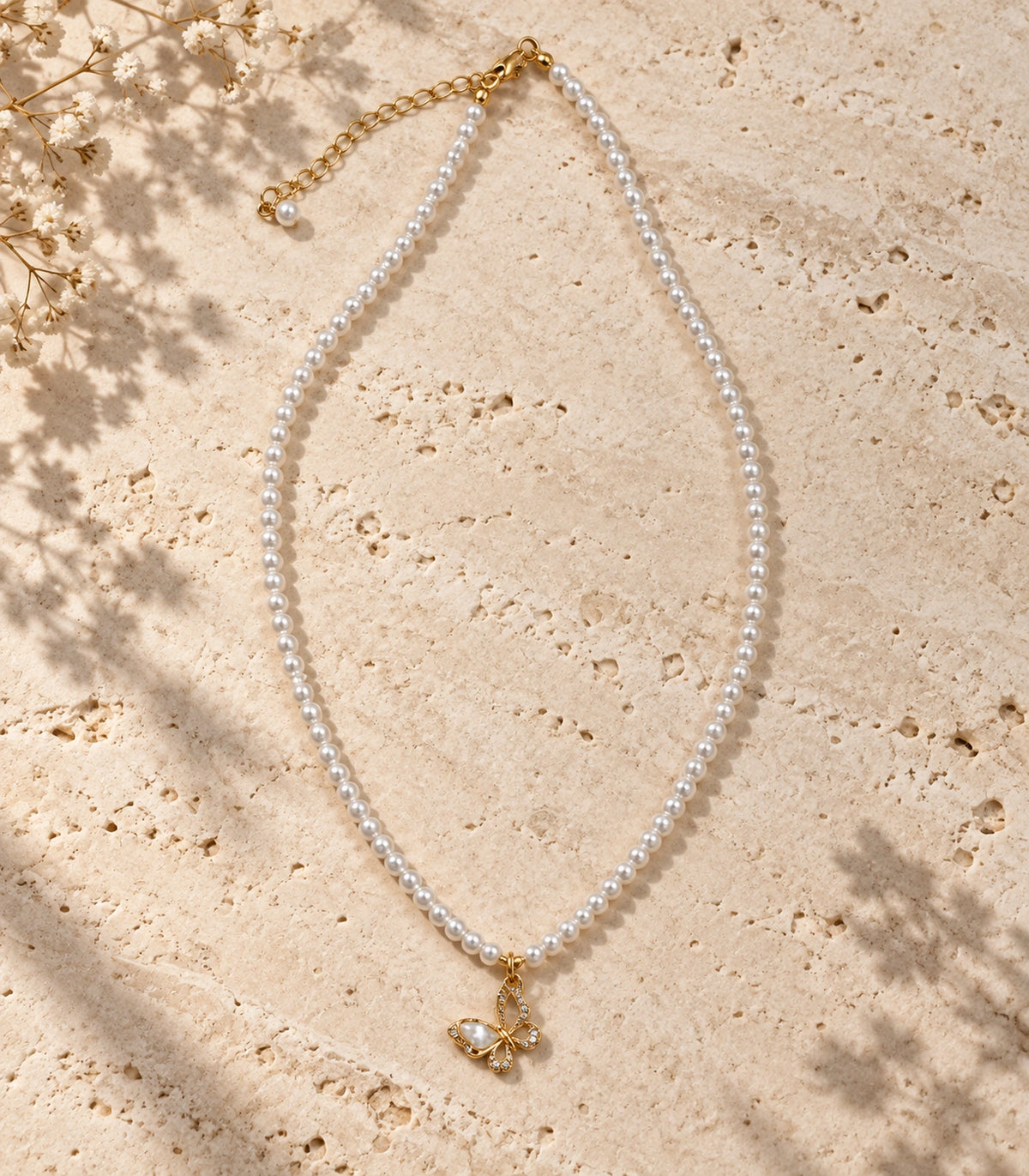 JIMIKI Gold-Tone Butterfly Pearl Necklace in Gold-tone / white, arranged in an editorial flat lay