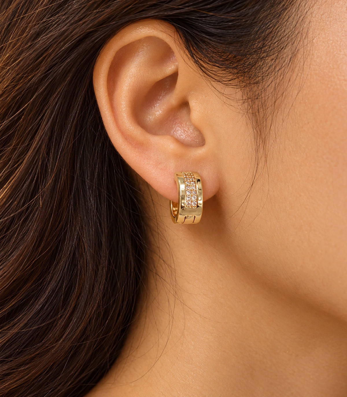 JIMIKI Gold Tone central pave strip huggie hoop earrings, worn in warm light #color_gold-tone