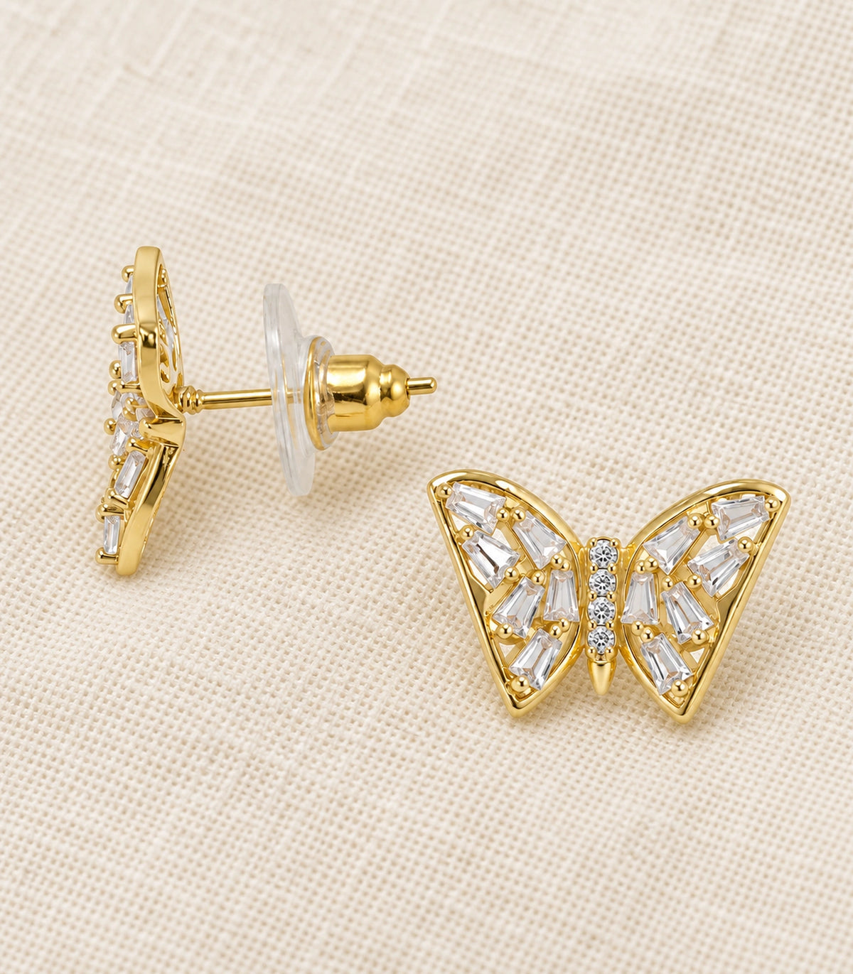 JIMIKI Gold Tone Clear Baguette Butterfly Stud Earring Pair in Gold tone, editorial flat lay