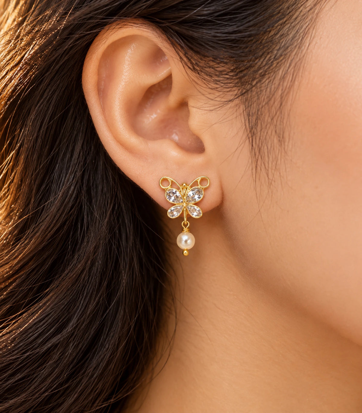JIMIKI Clear Crystal butterfly pearl drop earrings, worn in warm editorial lighting #color_clear-crystal
