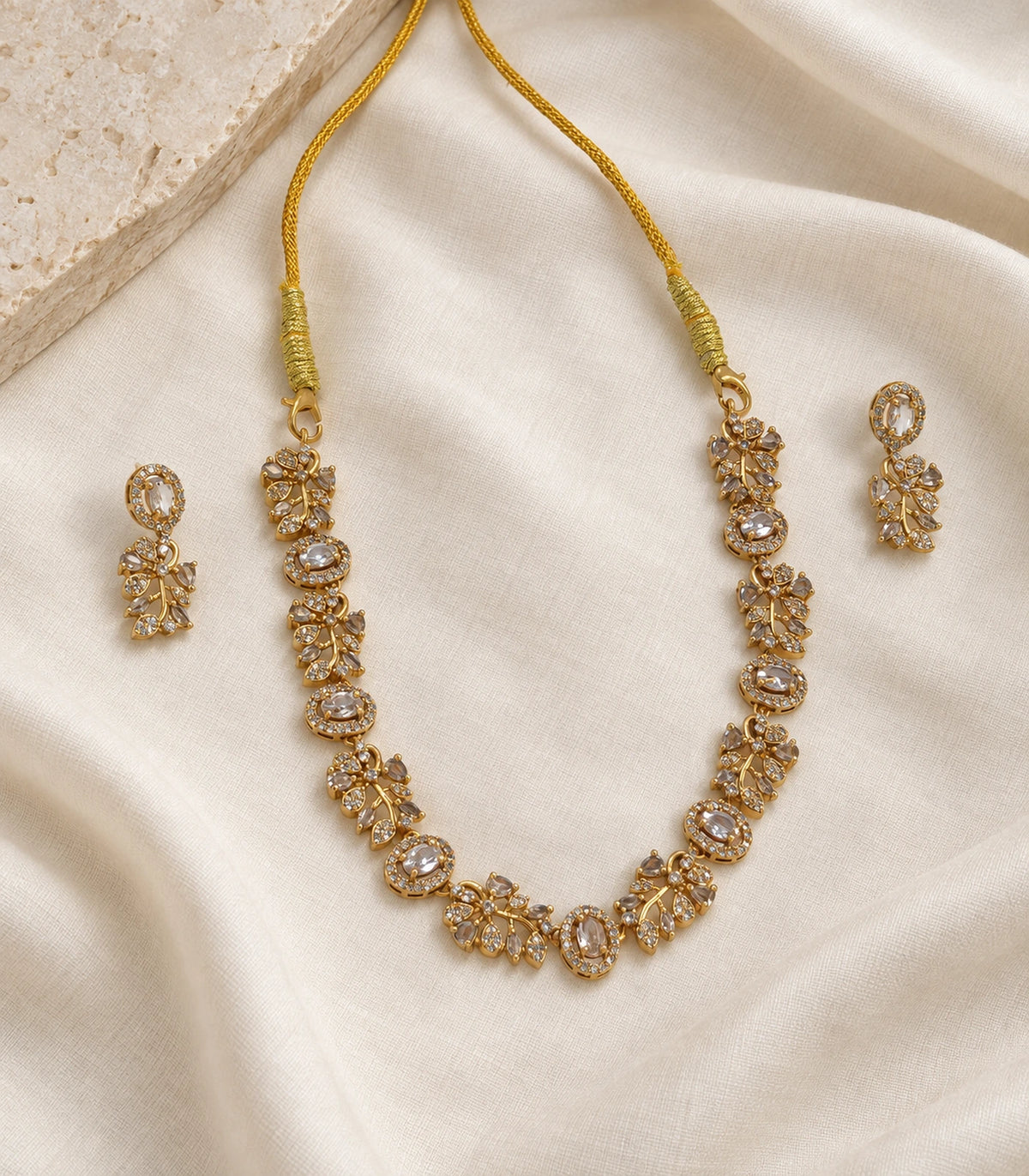 Clear Crystal Floral-Link Necklace Set with matching earrings arranged on ivory fabric #Color_Clear Crystal