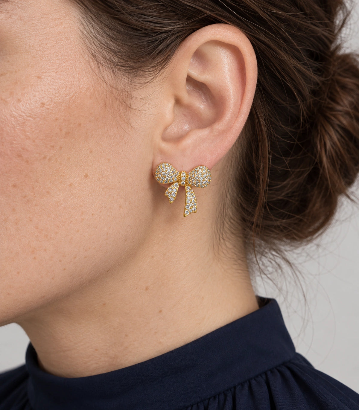 JIMIKI Pave Ribbon Bow Stud Earring Pair in Gold-tone, model wearing view #color_gold-tone