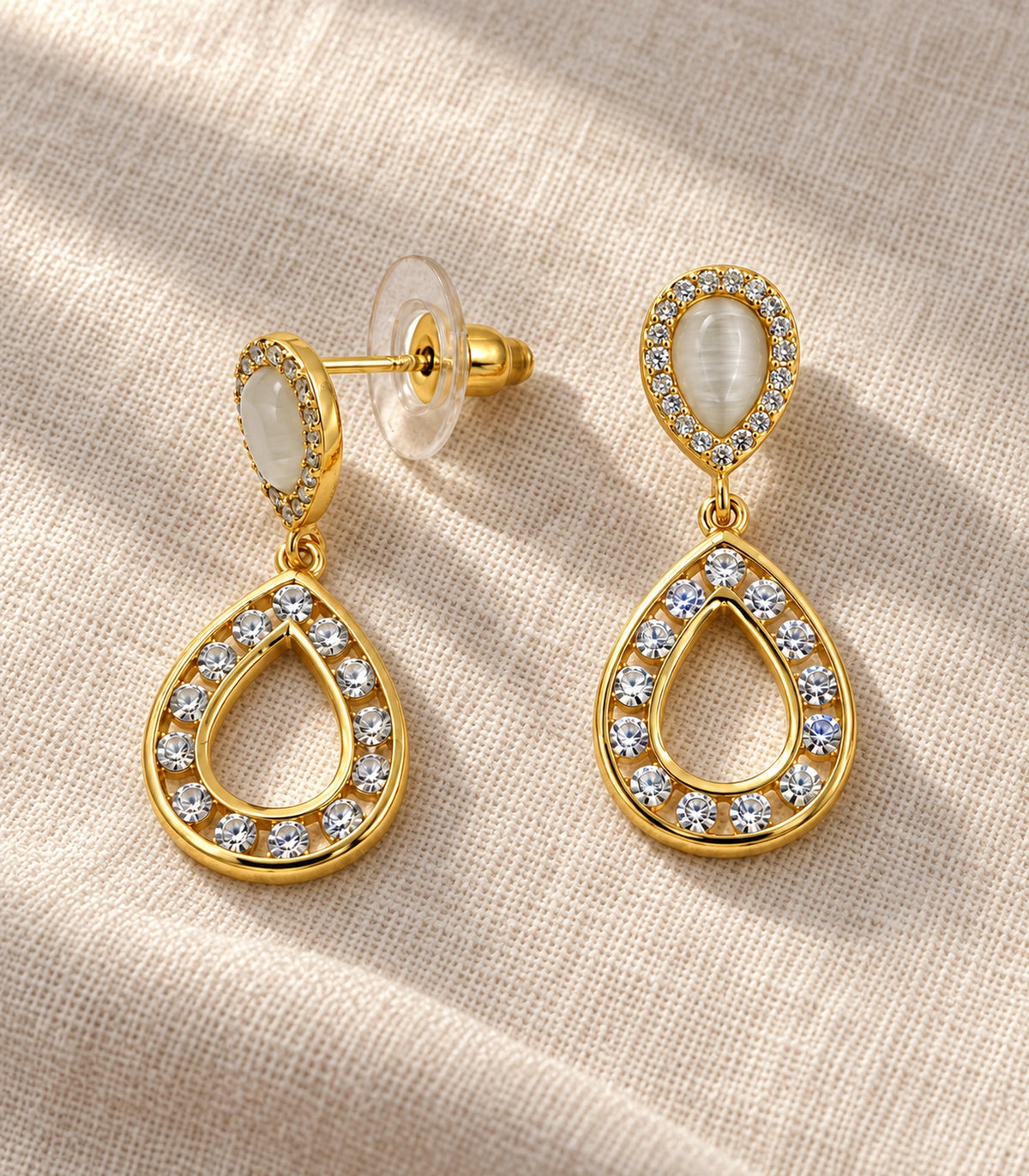 JIMIKI Gold Tone Cream Teardrop Crystal Halo Drop Earring Pair in Gold tone / Cream, editorial flat lay