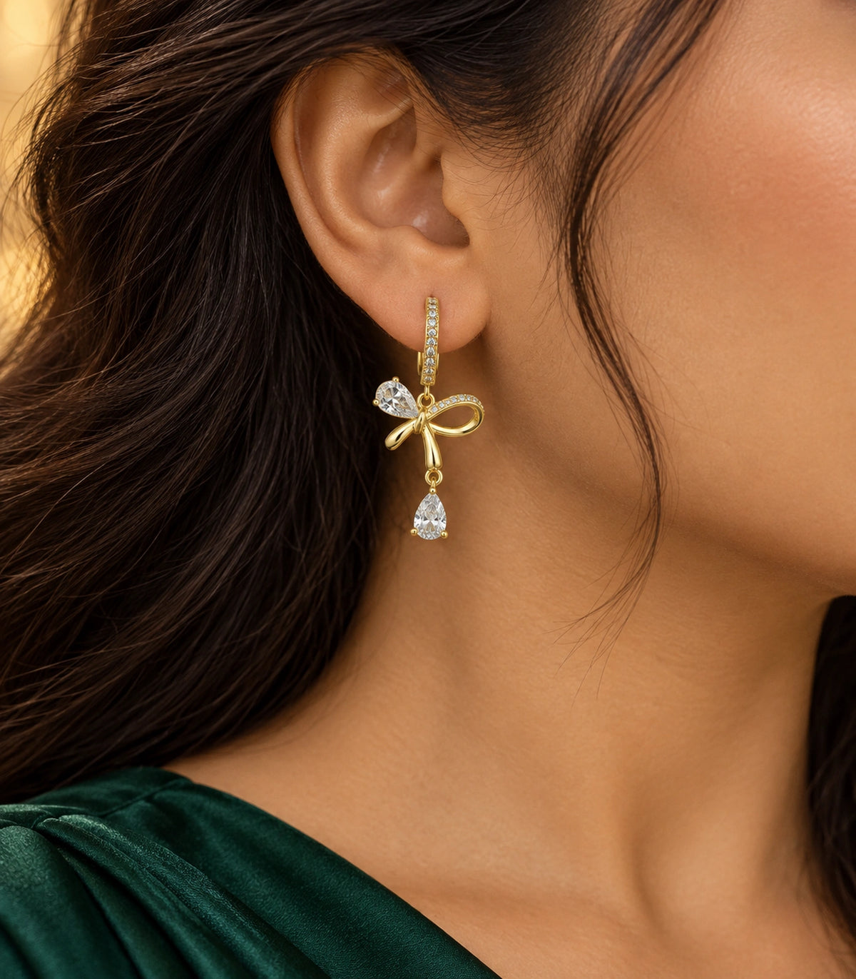 JIMIKI Gold-Tone Crystal Bow Drop Huggie Earrings in Gold / Clear, editorial model view