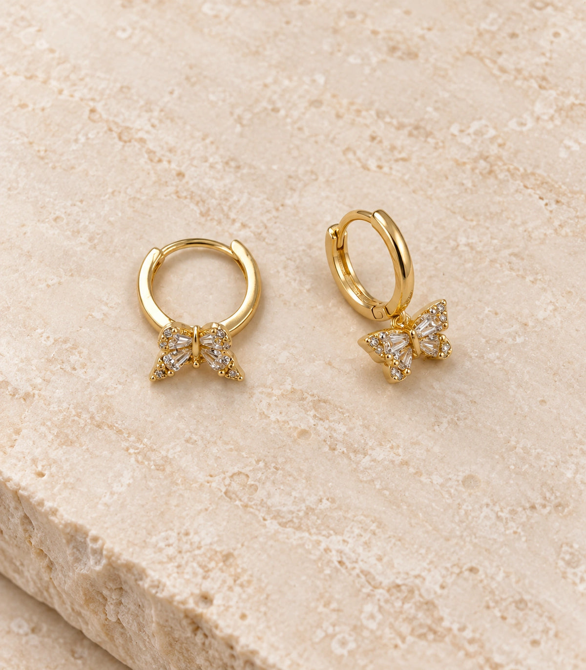 JIMIKI Crystal Butterfly Huggie Earrings in Gold / Clear, editorial flat lay #color_gold / clear